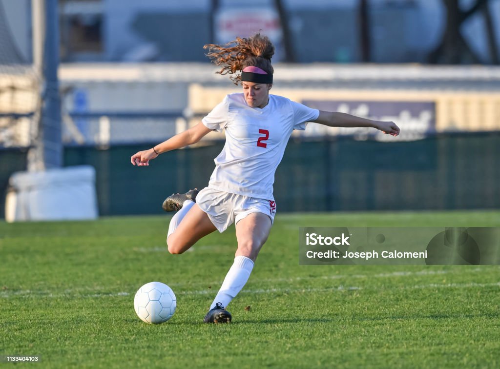 Menina atlética nova que joga com uma esfera de futebol em um campo de grama verde - Foto de stock de Futebol royalty-free