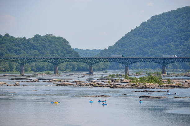 Scenic view of the Potomac River, with people lounging on lazy river tubing floats in the water on a hot summer day Harpers Ferry, West Virginia - July 2, 2018: Scenic view of the Potomac River, with people lounging on lazy river tubing floats in the water on a hot summer day harpers ferry photos stock pictures, royalty-free photos & images