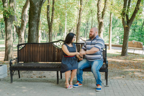 istock Two people in love sit on a bench in the park 1133404480