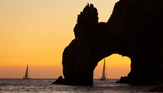 Sailboats through the Arch of Los Cabos viewed from boat