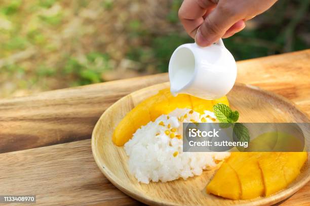 Mango With Sticky Rice Woman Hand Pouring Coconut Milk On Top With Beans Topping Stock Photo - Download Image Now