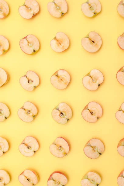 istock Background of cut in half apples on yellow background 1133412974