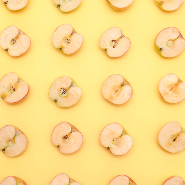 istock Background of cut in half apples on yellow background 1133413003