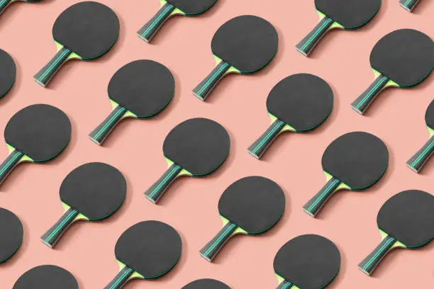 Black ping pong paddle on pink background. Pattern for your design