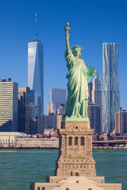 estatua de la libertad y horizonte de la ciudad de nueva york con manhattan lower east side, centro de comercio mundial, beekman tower y woolworth building, ny, ee. uu. - clear sky vacations vertical saturated color fotografías e imágenes de stock