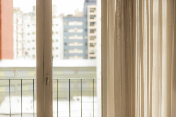 istock Window with curtain and bright light with city background 1133424058