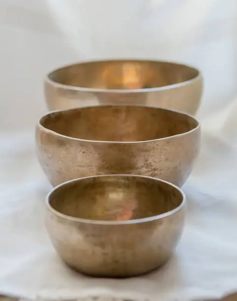 Three different sizes of singing bowls in front of each other