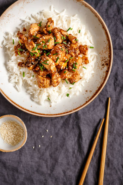 istock Top view on sesame chicken pieces with rice on a ceramic plate. Chinese traditional dish. Copy space. 1133426274