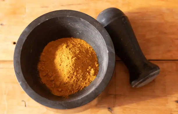 Photo of Turmeric powder in a mortar and pestle.