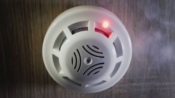 Low angle shot: The smoke detector is triggered by a trickle of dum, the red indicator lights up stock photo