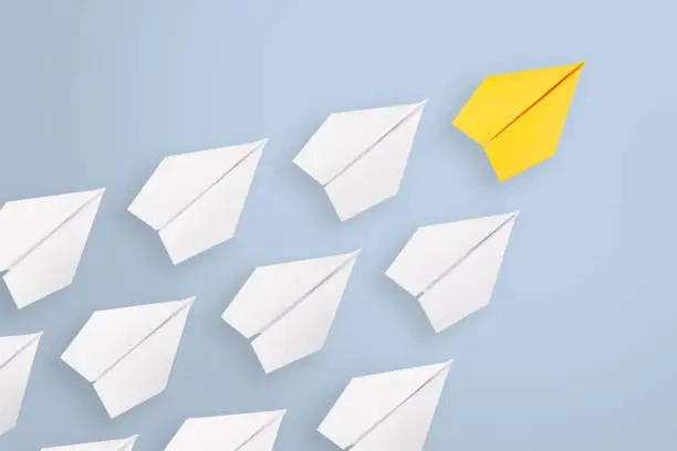 Photo of Leadership concepts with yellow paper airplane leading among white