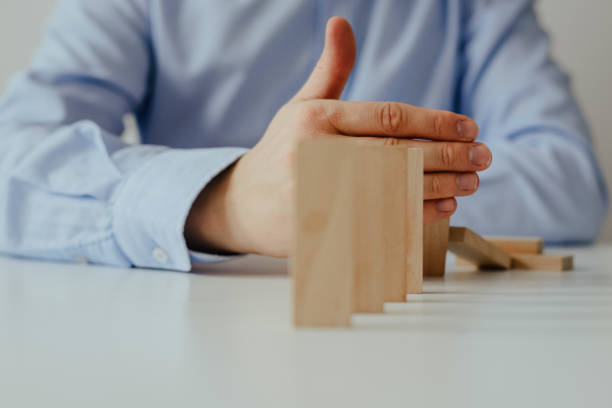 istock Businessman hand Stopping Falling wooden Dominoes for business solution effect from continuous toppled or risk, strategy and successful intervention. 1133439343