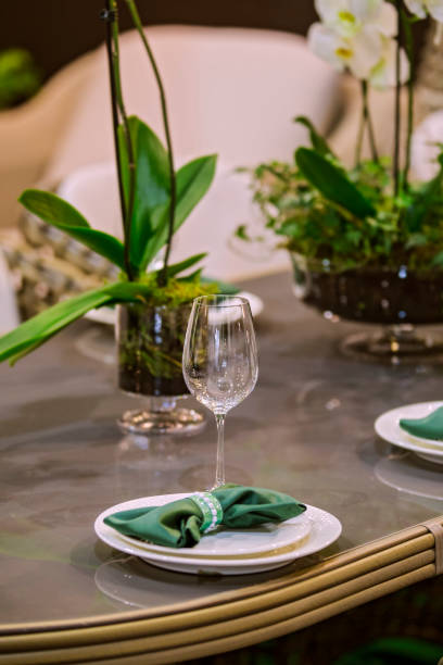 istock Restaurant table in eco style with green elements, wooden table, live orchids, glasses, plates, feast 1133440860