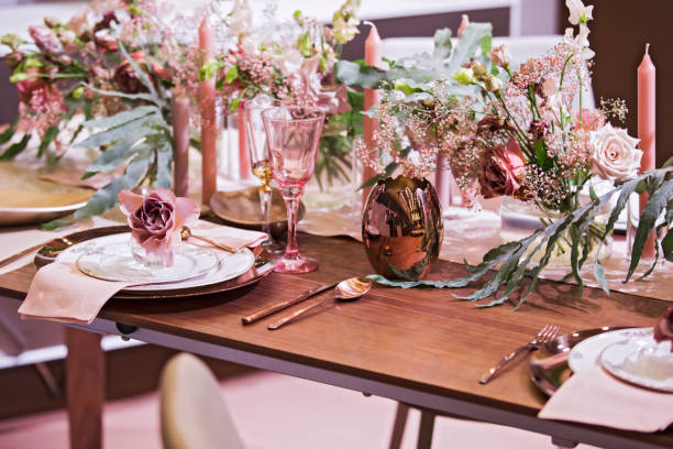 Table setting in pink color, for a wedding or other event, wine glasses, plates, spoons, forks, flowers and vases