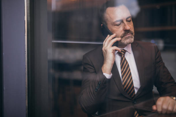 istock Senior man in suit is talking on mobile phone 1133441738