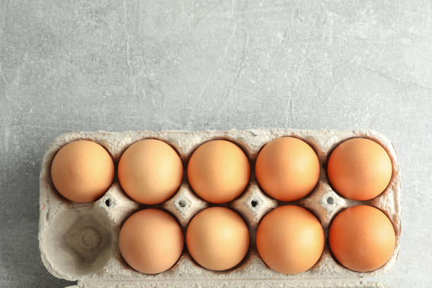 istock Chicken eggs in carton box on gray background, space for text 1133446943