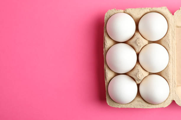 istock Chicken eggs in carton box on pink background, space for text 1133446953