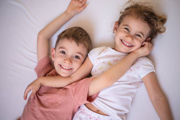 istock Beautiful brother and sister lying down on bed and looking at camera 1133446991