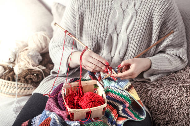 istock woman knits knitting needles on the couch 1133449796