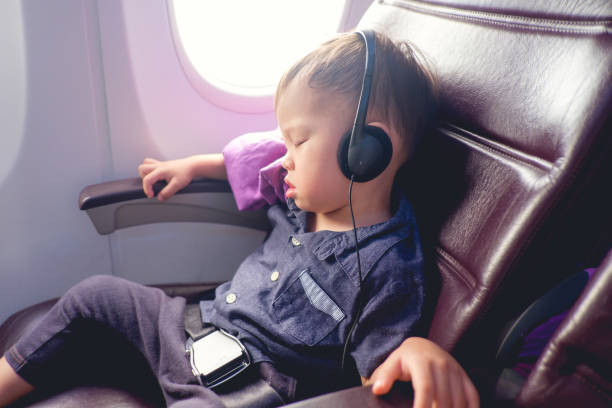 carino piccolo asiatico 24 mesi / bambino bambino di 2 anni bambino che dorme su aereo, bambino seduto con cintura di sicurezza su indossare le cuffie - toddler music asian ethnicity child foto e immagini stock