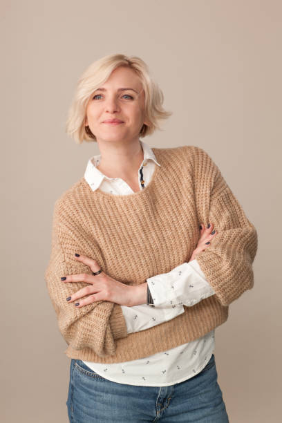 studio portret atrakcyjnej 40-letniej blondynki w beżowym swetrze na beżowym tle - 30s women sweater female zdjęcia i obrazy z banku zdjęć