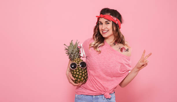 porträt von hipster-mädchen und ananas isoliert auf rosa hintergrund - fashion model women cleavage human hair stock-fotos und bilder