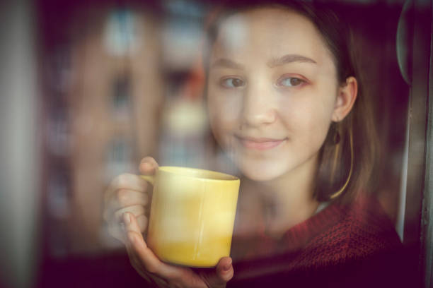 istock Happy girl drinking tea or coffee and looking through the window 1133452105