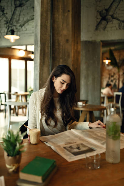 istock Young woman relaxing in a cafe while reading newspaper during her coffee time. 1133453649