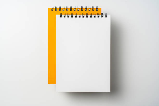 istock two spiral orange notebook and pen on white 1133454601