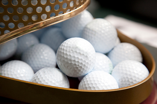 A container of white golf balls at a pro shop ready for sale or to be owned
