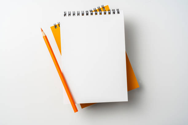 istock two spiral orange notebook and pen on white 1133454640