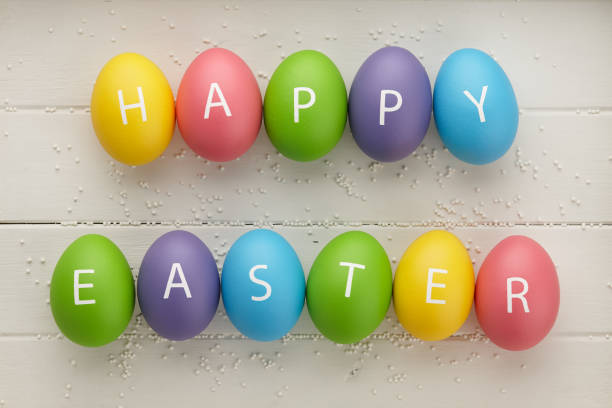 colorful easter eggs with letters on white planks - easter text single word paint imagens e fotografias de stock