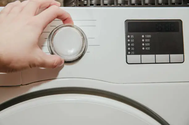 Photo of Doing the laundry. The man presses the start of the washing machine.