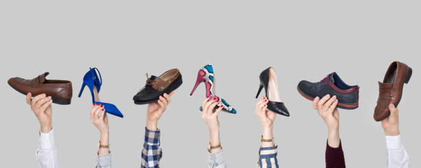 istock Hands holding different shoes on gray background 1133465153