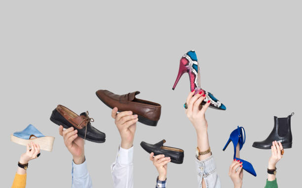 istock Hands holding different shoes on gray background 1133465167