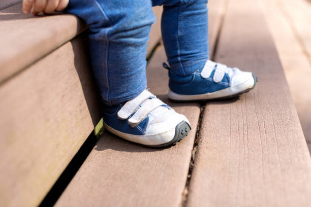 Toddler boy wearing his blue sneakers outside