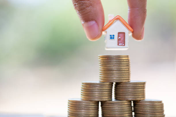 istock Human hand putting house model on coins stack. Concept for property ladder, mortgage and real estate investment 1133472006