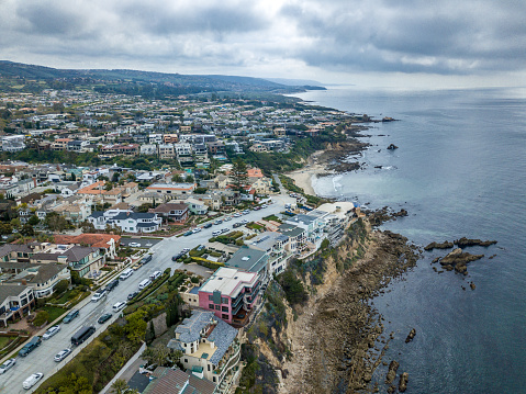 An aerail view of the stunning Corona Del Mar cliffs and coastline looking south to Laguna Beach. Luxury homes along the coastal cliff and stunning rock formations dot the coastline.