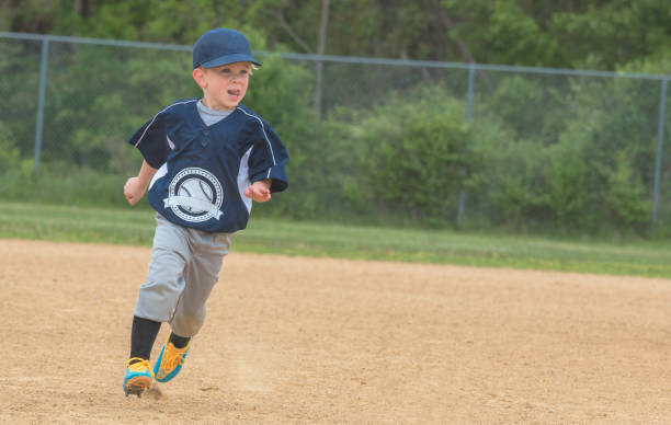 a young baseball player running the bases during a baseball game - base runner imagens e fotografias de stock