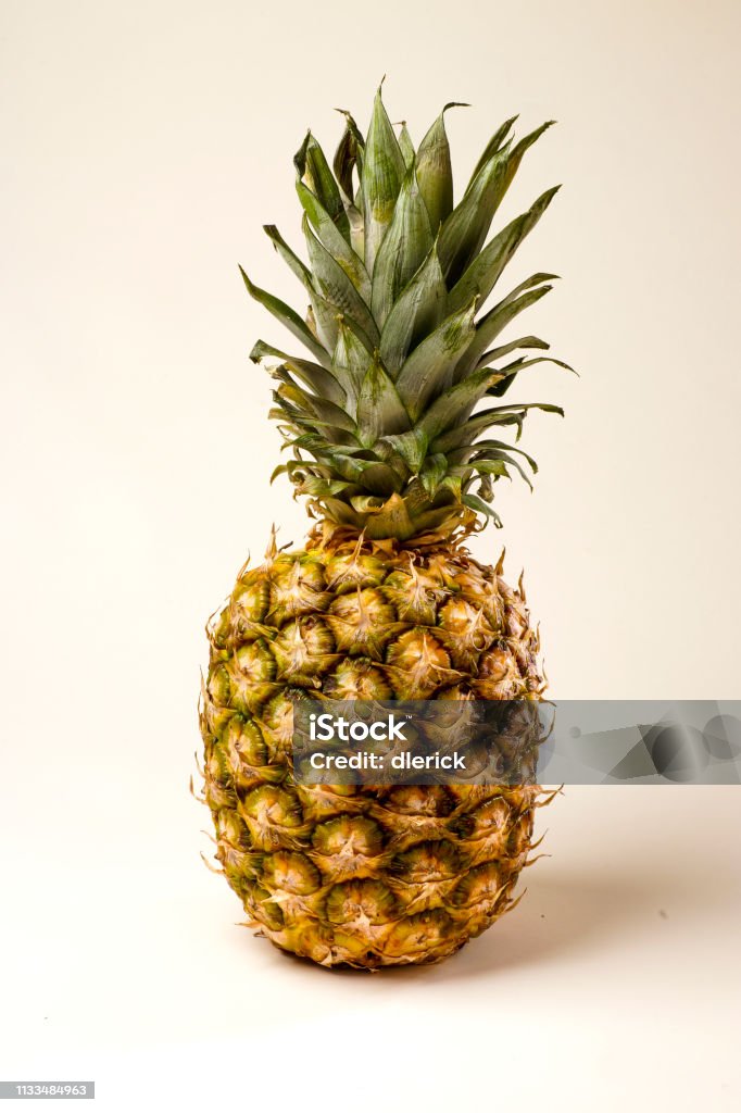 Ripe Pineapple on White Background Ripe pineapple standing upright complete with green fronds. Backgrounds Stock Photo