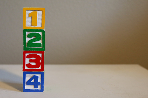 Colorful wood number blocks of 1 2 3 4 in yellow, green, red, and blue. One Two Three Four.