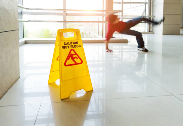 Man slips falling on wet floor Man slips falling on wet floor next to the wet floor caution sign. slippery stock pictures, royalty-free photos & images