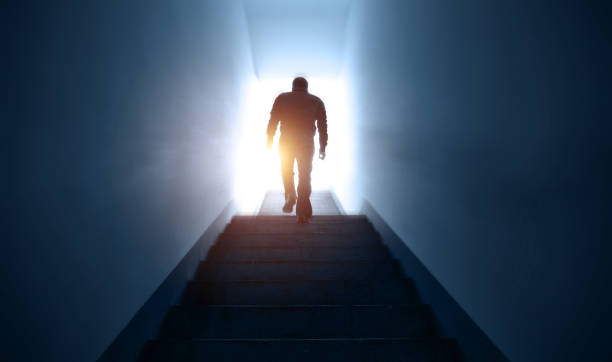 man walking upstairs into the light. - upstairs imagens e fotografias de stock