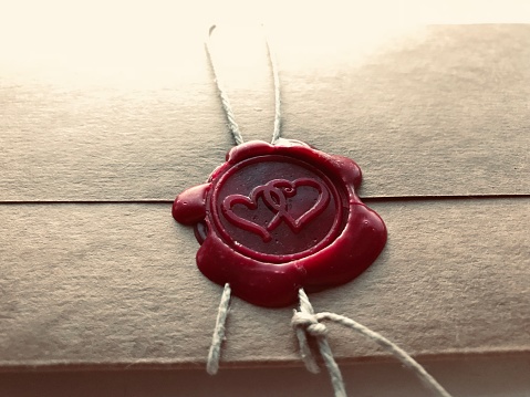 Red wax seal with two hearts on old paper.