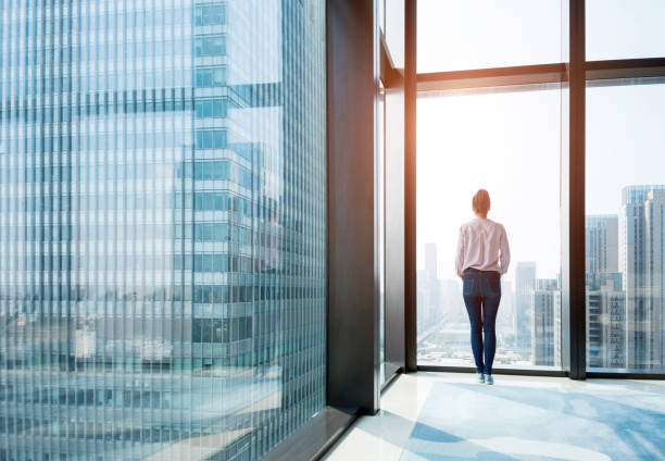 frau stehen und blickte cityscape - looking through window window business women stock-fotos und bilder