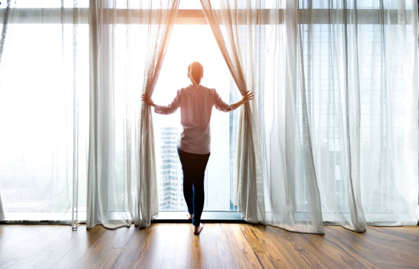 Woman opening curtains and looking out