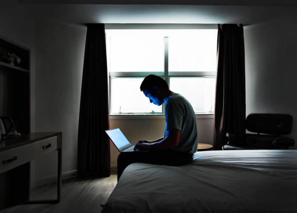 homme s'asseyant dans le bâti avec un ordinateur portatif - hotel wireless technology bedroom hotel room photos et images de collection