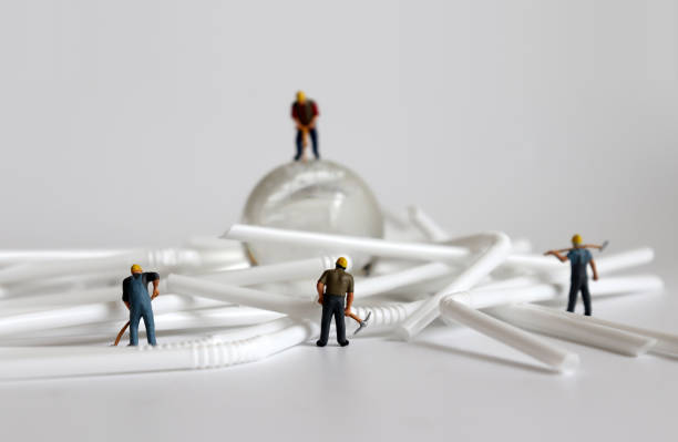 istock Miniature workers with disposable plastic straws. Concepts about the overflow of disposable plastic product waste. 1133502655