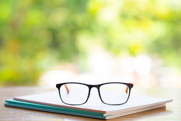 istock Black eyeglasses with three white notebook on wooden table, Bokeh garden background, Close up & Macro shot, Selective focus, Stationery concept 1133506713