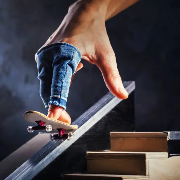 Photo of Riding a mini skateboard on a special track. Hand with fingerboard closeup